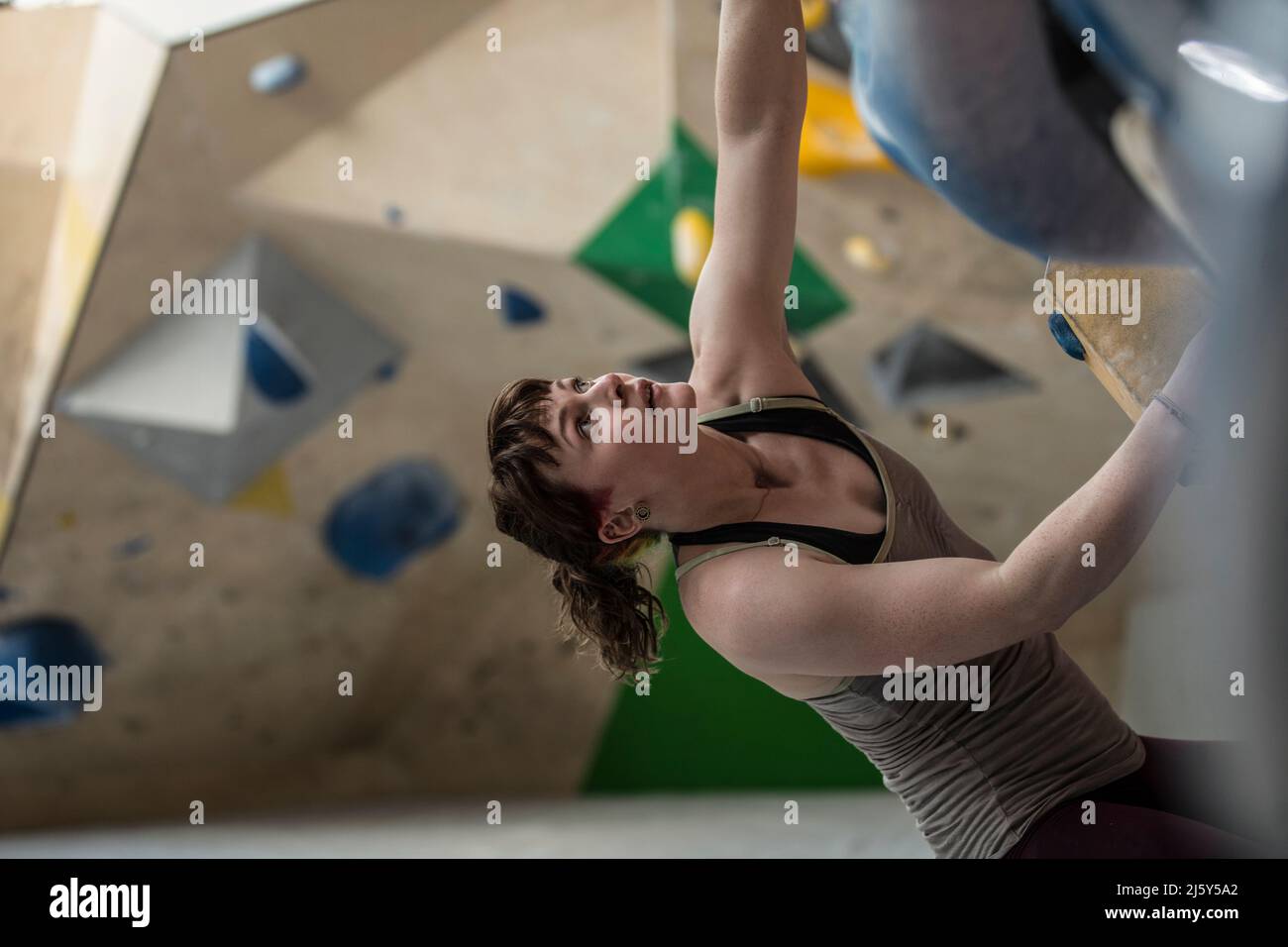 Giovane scalatore di roccia femminile che guarda in alto al muro di arrampicata Foto Stock