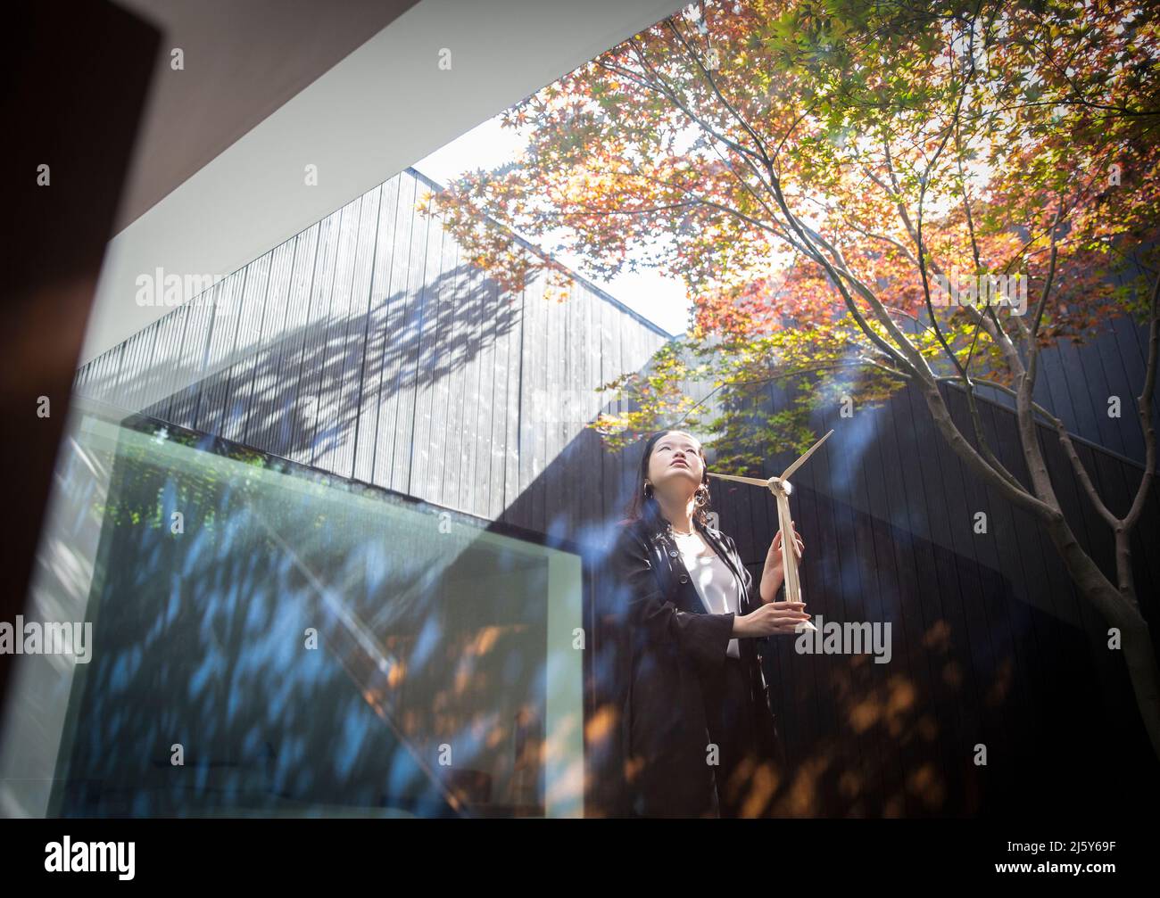 Ingegnere femminile con turbina eolica modello in piedi in cortile Foto Stock
