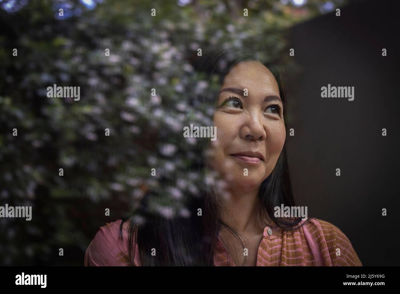Primo piano donna sorridente guardando fuori finestra con riflessione Foto Stock