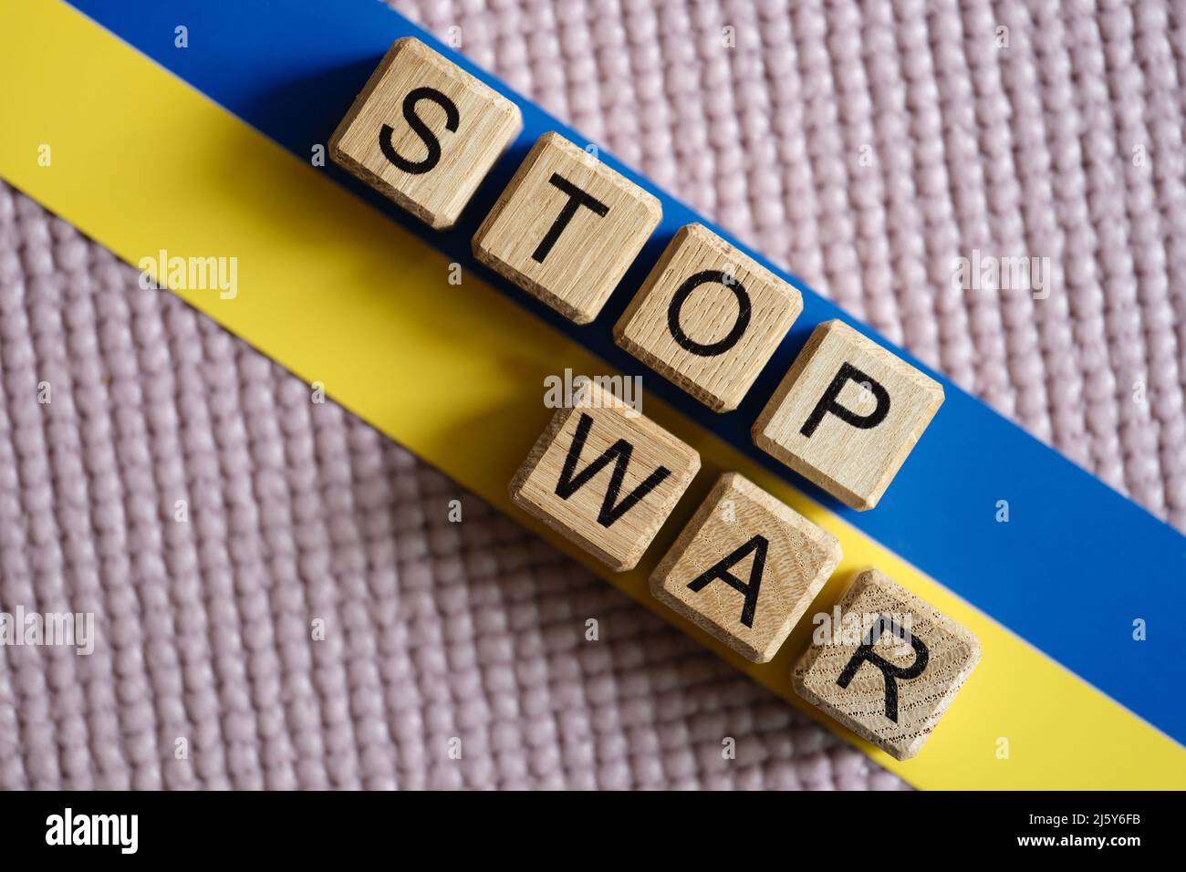 Stop guerra scritto su cubi di legno sullo sfondo della bandiera ucraino primo piano Foto Stock