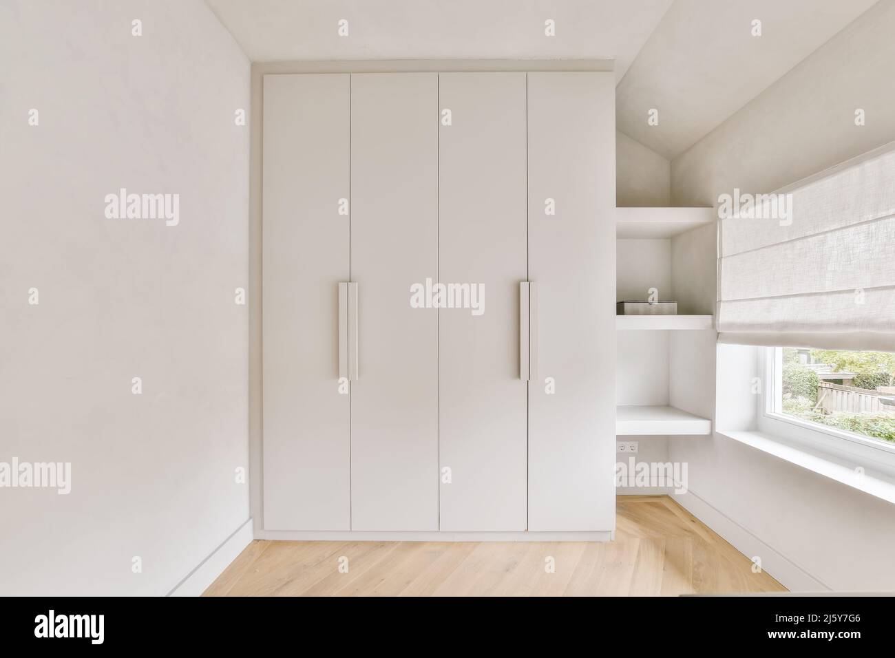 Elegante grande armadio bianco posto vicino alle pareti e mensole in camera  spaziosa e luminosa con jalousie su vetro finestra a casa Foto stock - Alamy
