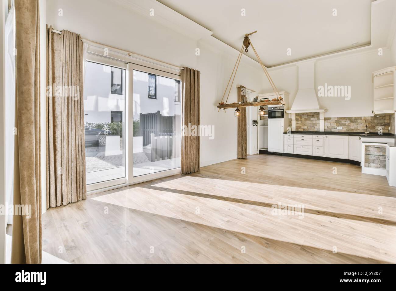 Interno di una spaziosa cucina con armadi bianchi e elettrodomestici incorporati in appartamento con pavimento in laminato Foto Stock