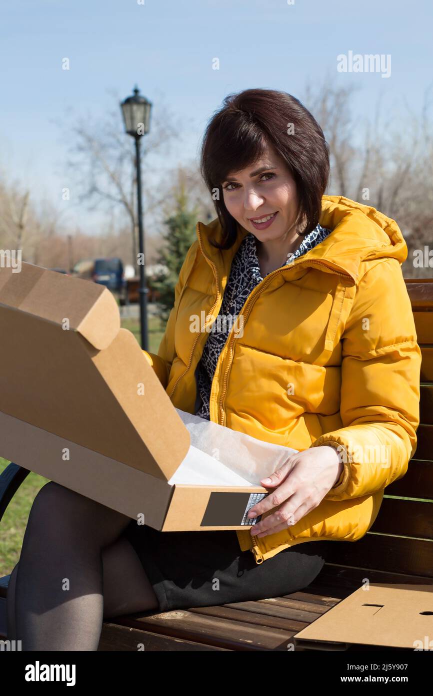 Una donna felice con un sorriso apre una scatola con una nuova strada portatile. Foto Stock