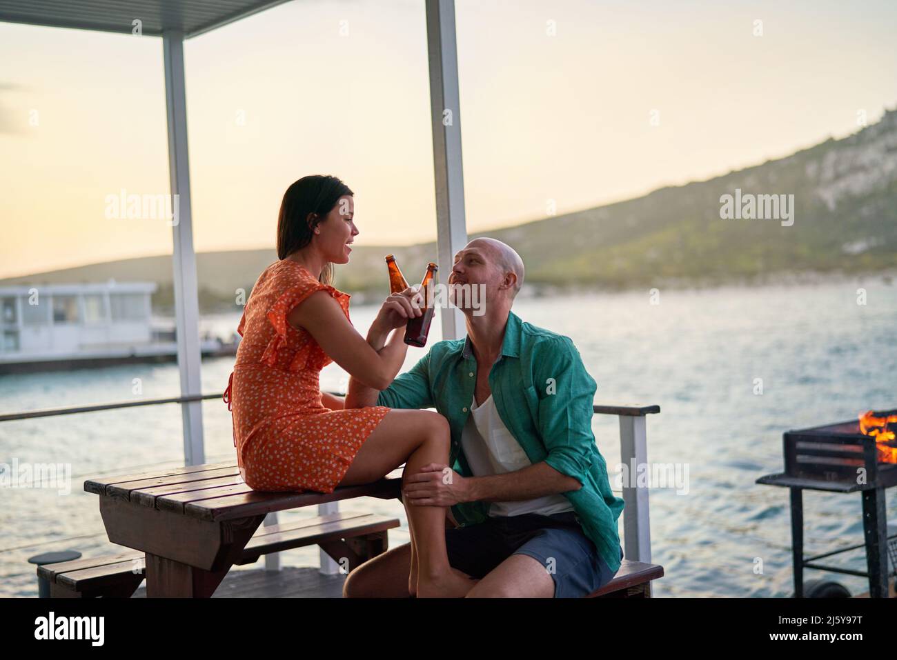 Coppia felice bere birre sul patio della casa galleggiante Foto Stock