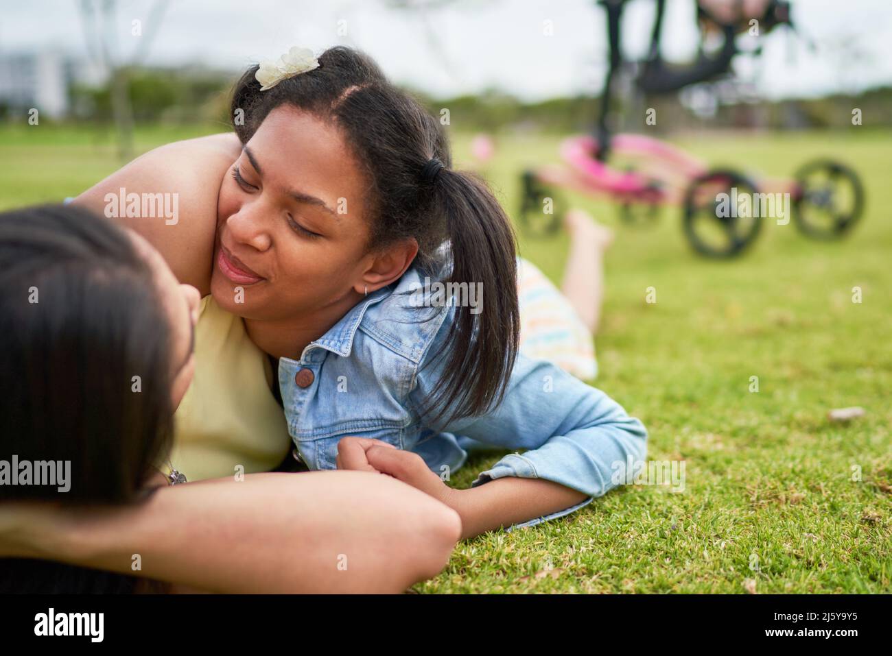 Madre affettuosa e figlia disabile che posa in erba parco Foto Stock