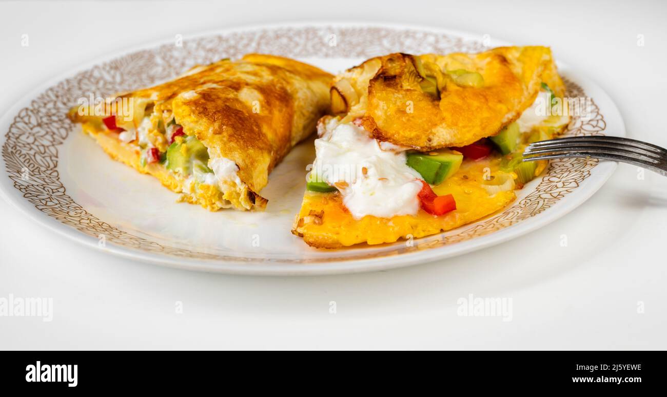 Frittata con avocado, pepe rosso, semi di lino, cipolla e yogurt su piatto con forchetta, primo piano. Colazione sana. Foto Stock