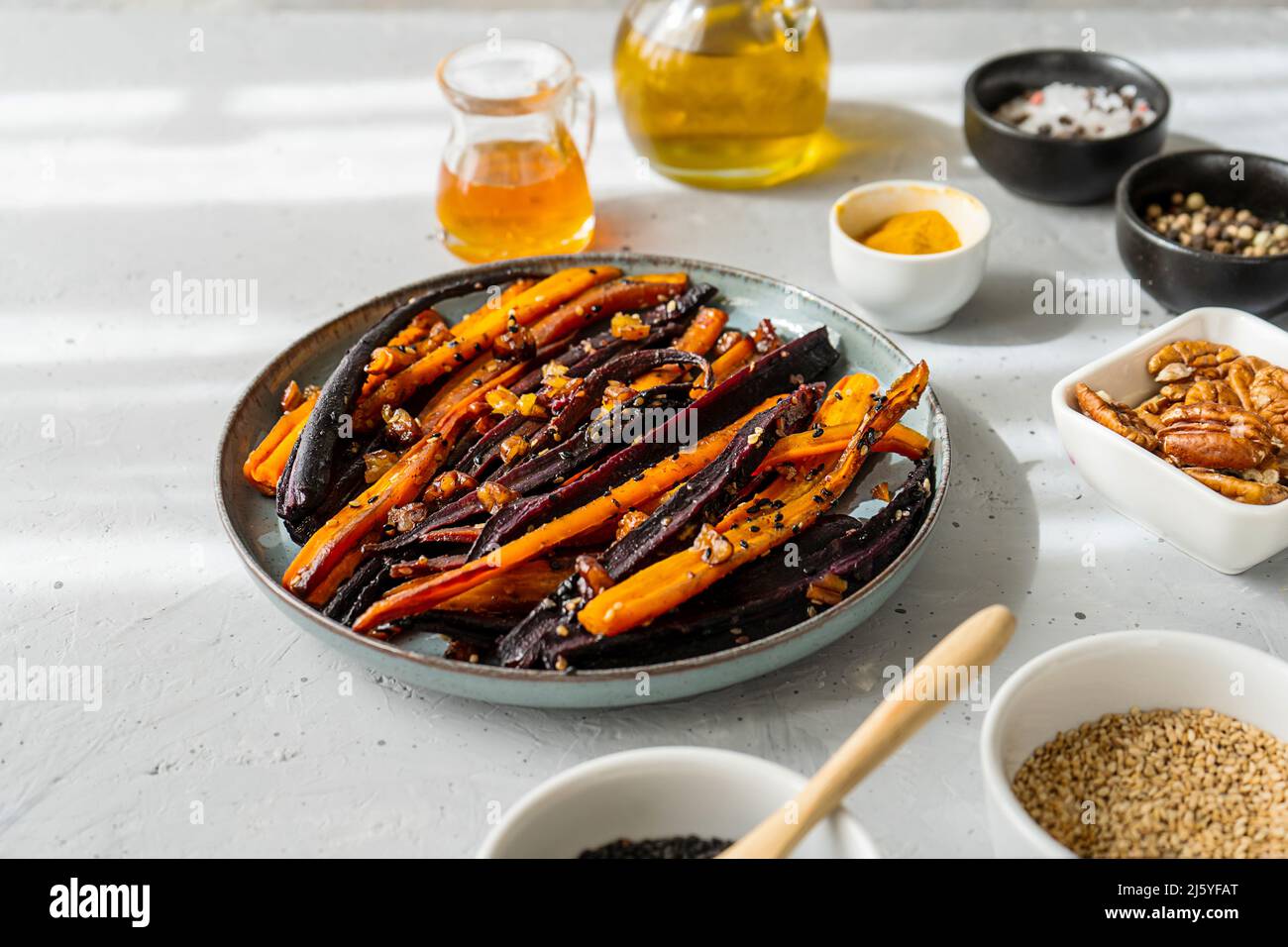Carote di viola piccante e arancio glassate con ingredienti su sfondo grigio. Primo piano Foto Stock