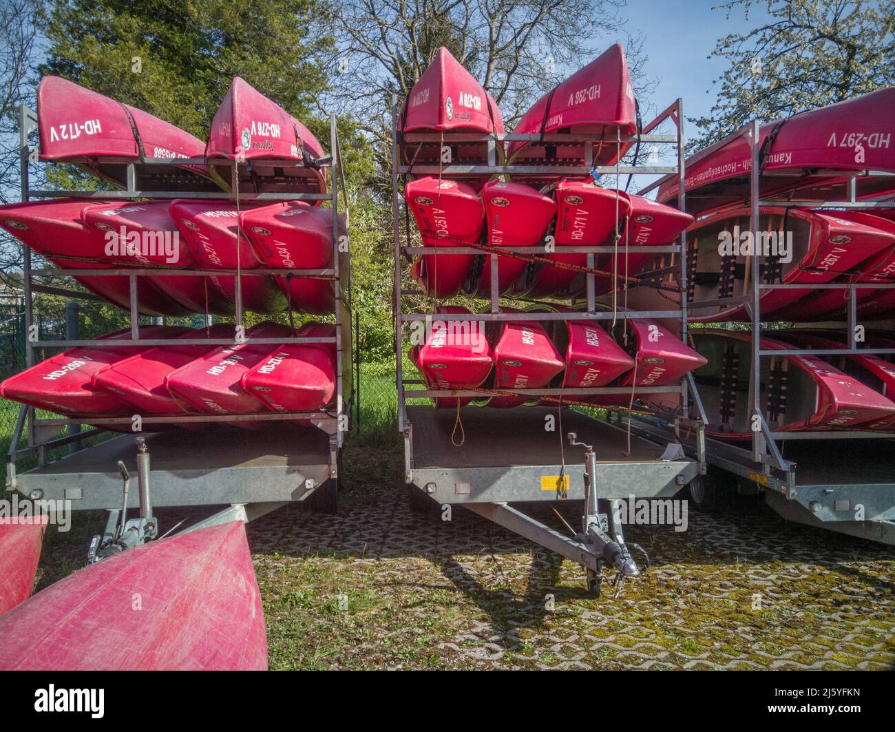 Neckargemuend, Germania: 11 aprile 2022: Canoe rosse su un rimorchio auto in primavera in attesa di essere utilizzato per tour turistici sul fiume in estate Foto Stock