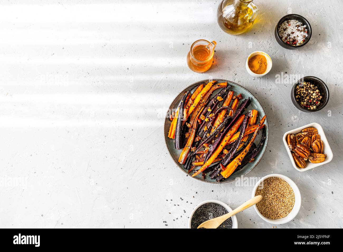 Carote di viola piccante e arancio glassate con ingredienti su sfondo grigio. Disposizione piatta. Spazio di copia Foto Stock