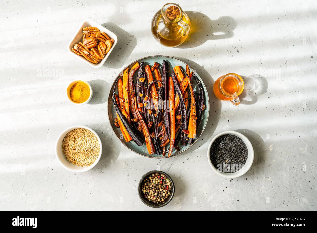 Carote di viola piccante e arancio glassate con ingredienti su sfondo grigio. Vista dall'alto Foto Stock