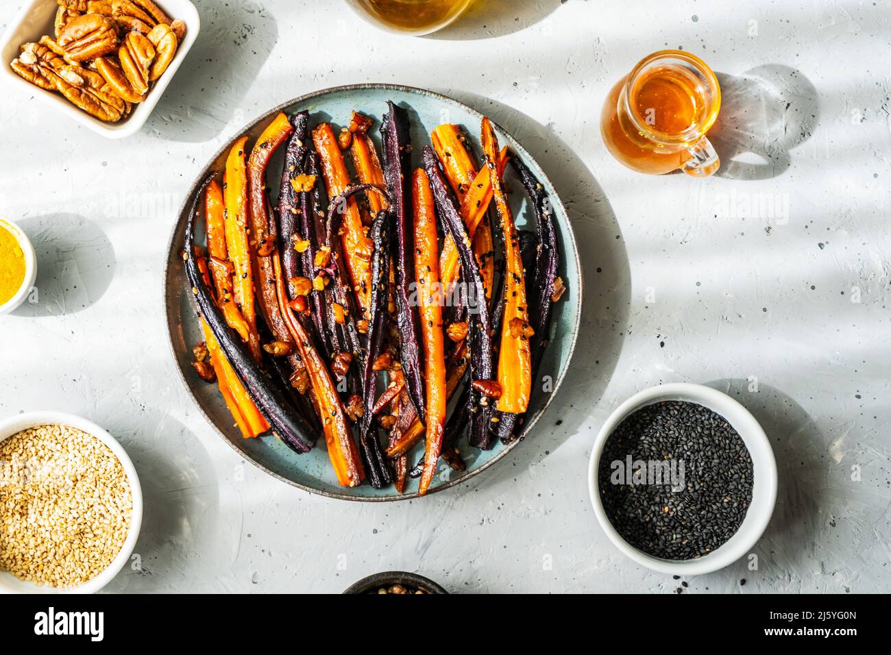 Carote di viola piccante e arancio glassate con ingredienti su sfondo grigio. Vista dall'alto Foto Stock
