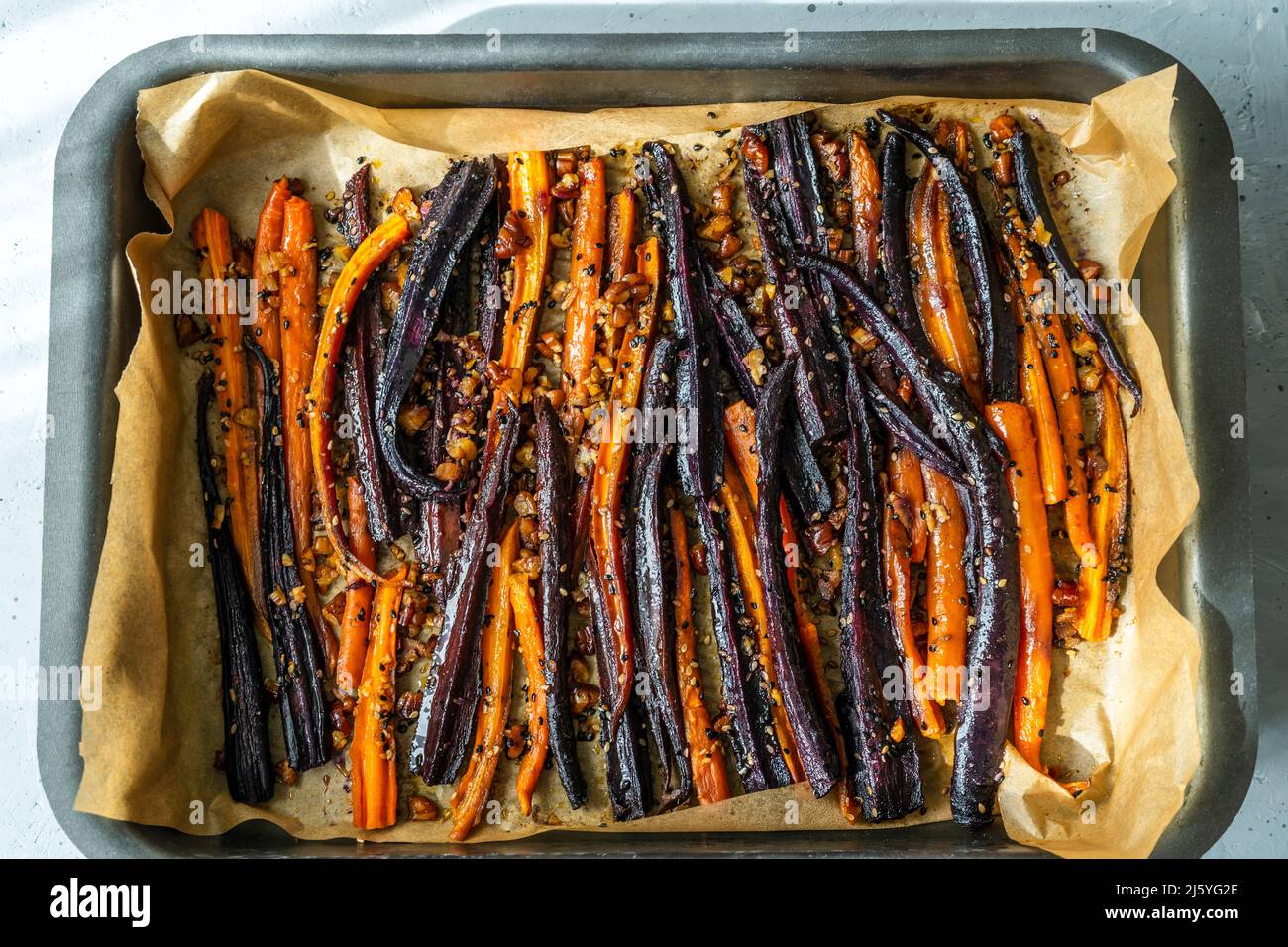 Carote di viola piccante e arancio glassate su foglio cotto. Vista dall'alto Foto Stock