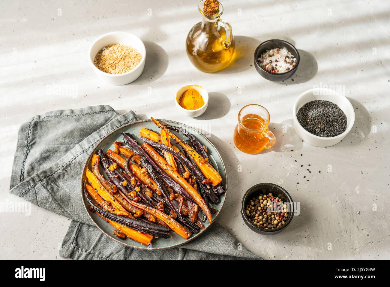 Carote di viola piccante e arancio glassate con ingredienti su sfondo grigio. Primo piano Foto Stock
