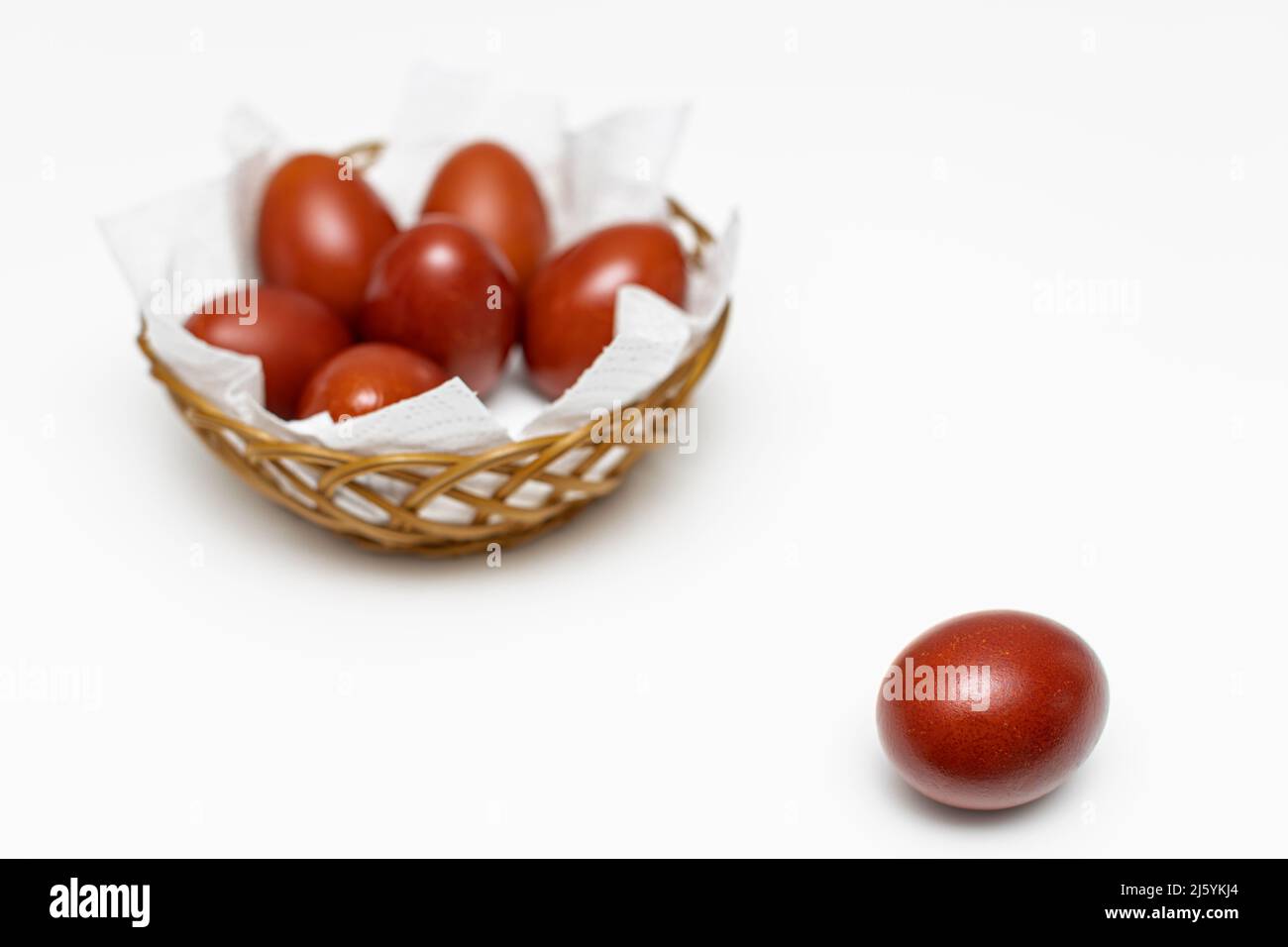 un uovo rosso di pasqua si trova sullo sfondo di un cestino con uova. Foto di alta qualità Foto Stock