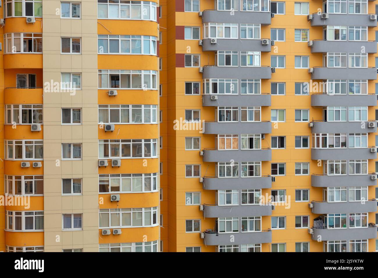 Sfondo con facciata di un edificio residenziale a più piani. Un vero e proprio edificio residenziale con tende, persiane e aria condizionata. Foto Stock