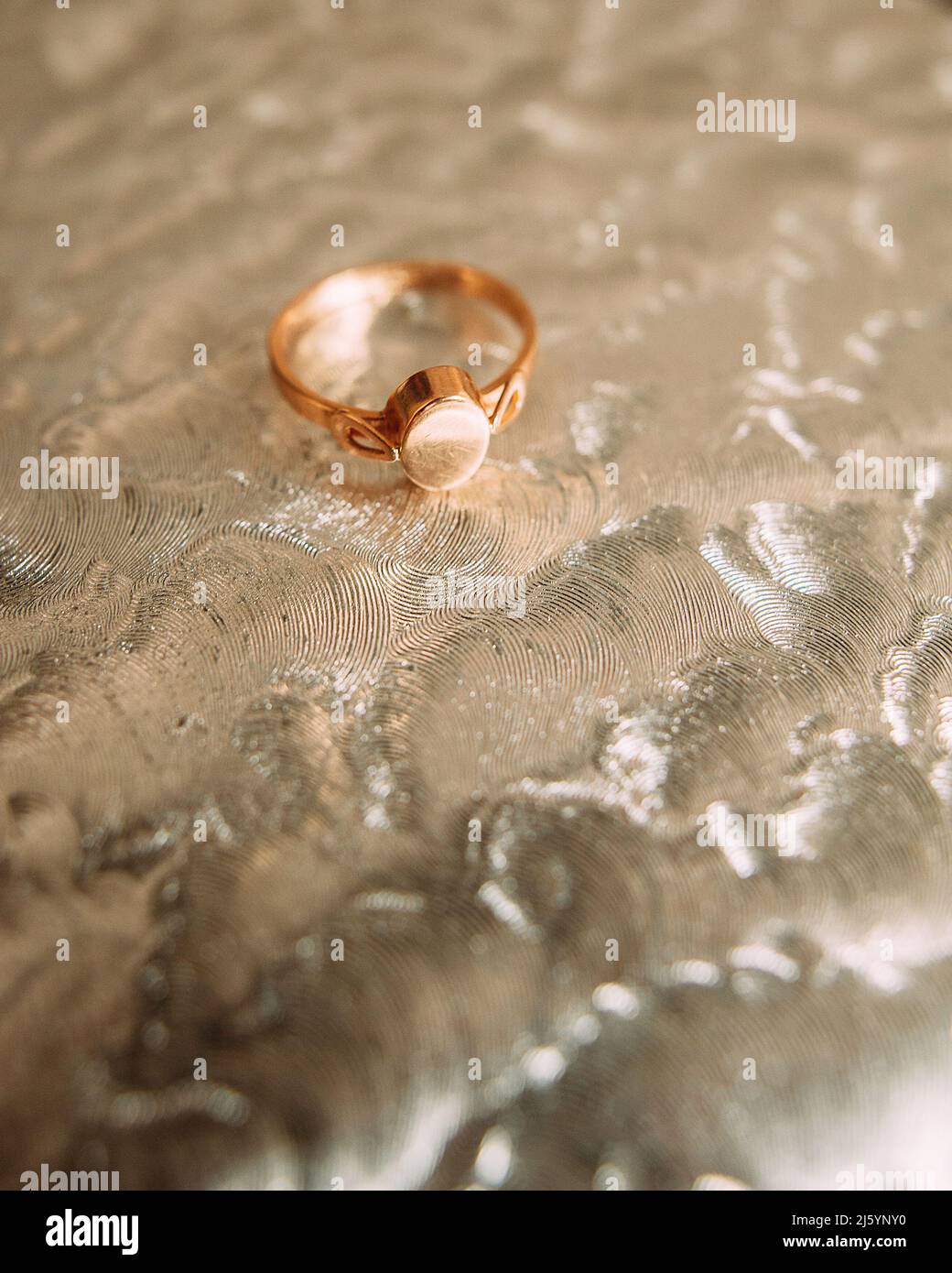 L'anello d'epoca d'oro rosso si trova su uno sfondo volumetrico argentato. Regalo per gli amati in occasione dell'anniversario, del matrimonio, del compleanno. Foto Stock