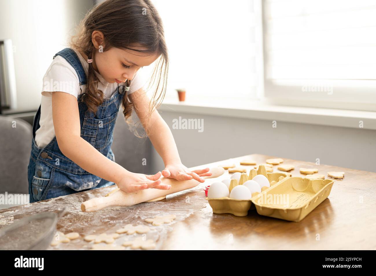 La ragazza del toddler cute che cucinano, impasta l'impasto, usando la spina di rotolamento, il bambino spende il tempo libero nel paese, cucinando i biscotti, godendo l'attività di fine settimana Foto Stock