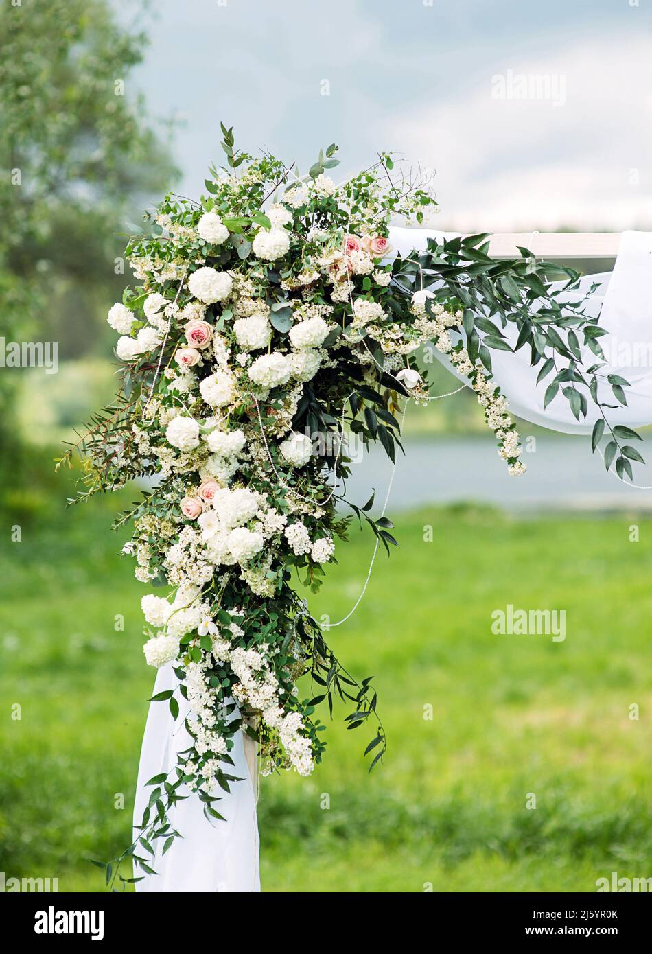 Decorazione floreale arco di nozze, arco di rose bianche con verde fresco da vicino, cerimonia di nozze rustica, cielo blu, cerimonia di nozze all'aperto. Foto Stock