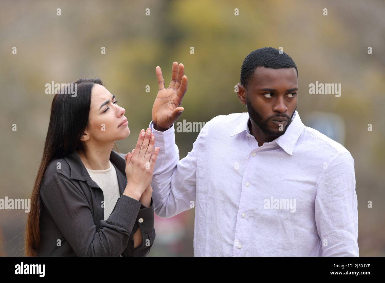 Uomo arrabbiato che rifiuta una donna che sta elemosendo in un parco Foto Stock