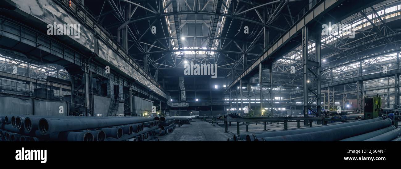 Foto panoramica del grande magazzino scuro in fabbrica per la produzione di tubi metallici. Foto Stock