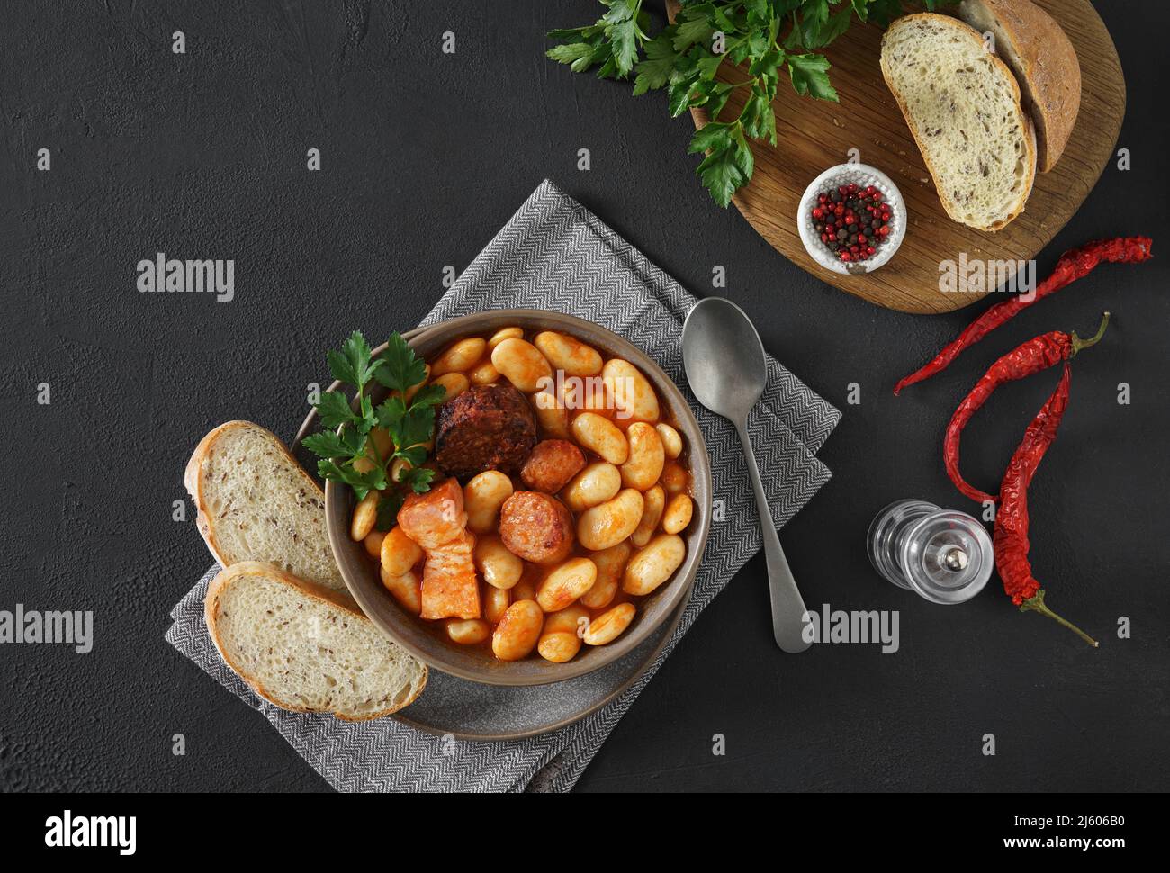 Ricetta tradizionale di fagioli con chorizo e salsiccia di sangue di Fabada Asturiana su un tavolo scuro. Vista dall'alto. Spazio copia Foto Stock