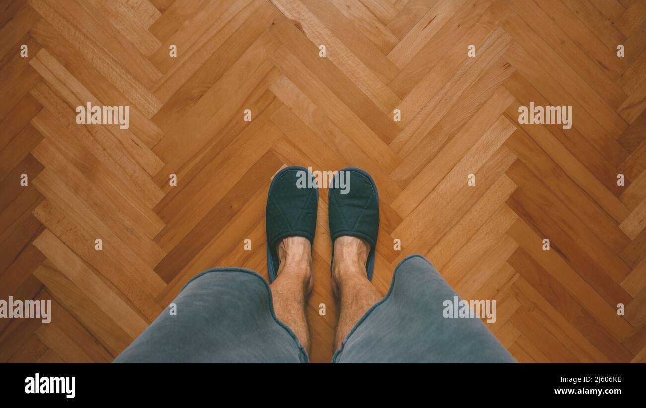 Uomo casual che indossa ciabatte a casa in piedi in camera da letto su parquet di quercia, vista dall'alto con spazio copia Foto Stock