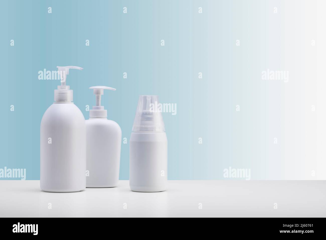 Set di tre erogatori per cosmetici, su una superficie bianca e uno sfondo azzurro Foto Stock