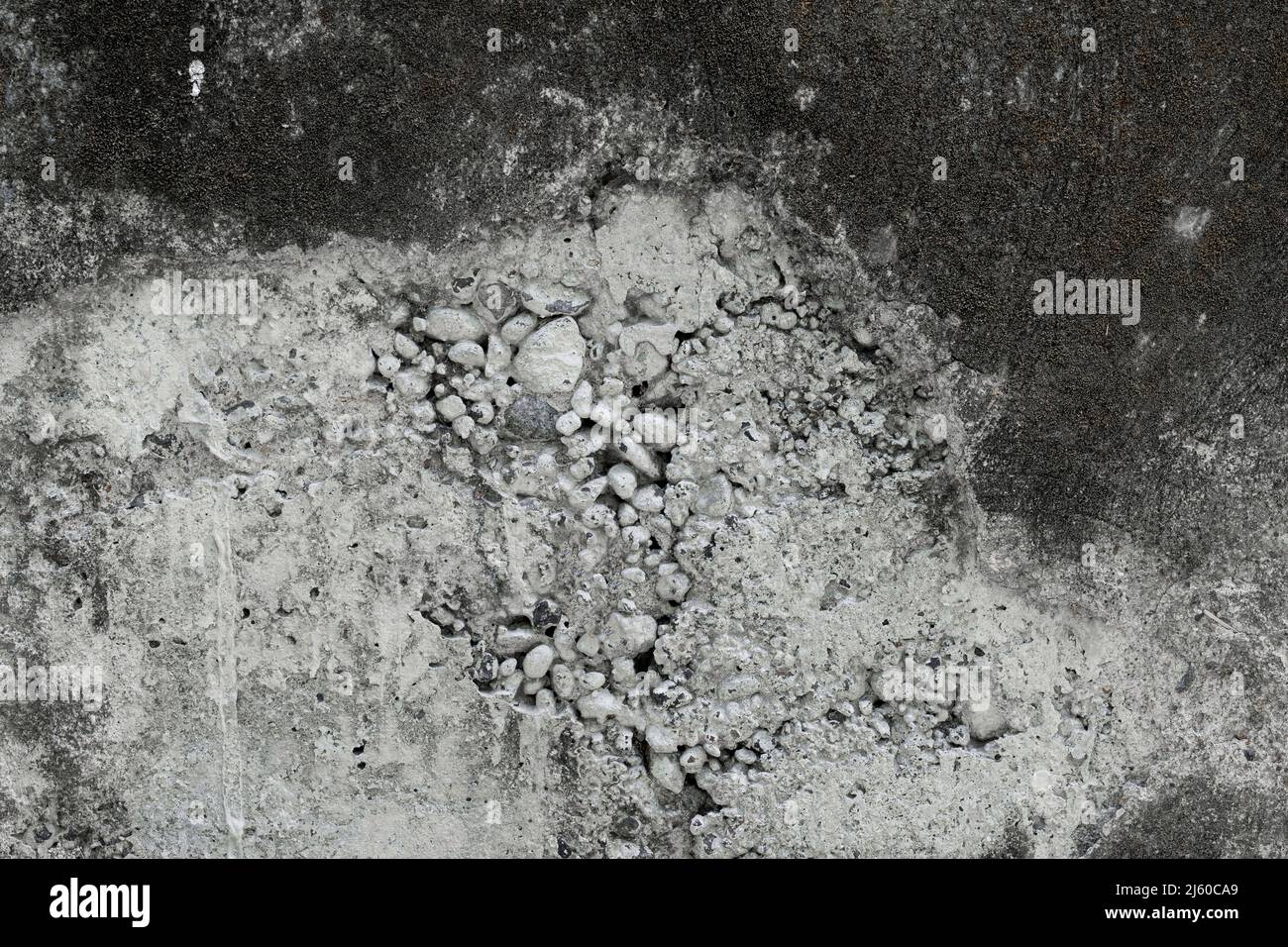 Muro di cemento bianco e nero con sbriciolamenti piccoli pezzi di calcestruzzo sciolto a forma di roccia caduta Foto Stock