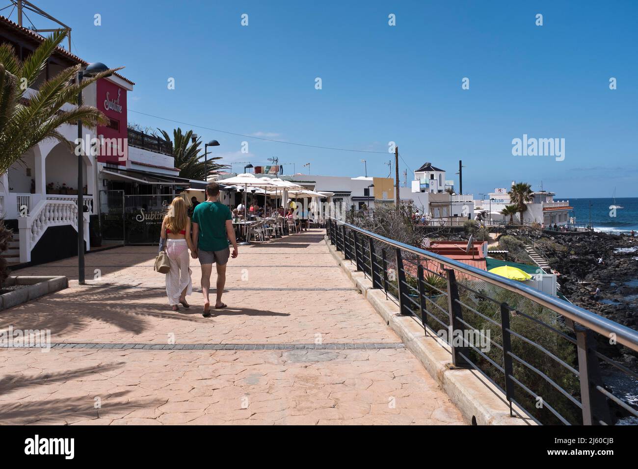 dh la Caleta Promenade COSTA ADEJE TENERIFE Coppia turistica a piedi prome costa vacanze resort Foto Stock