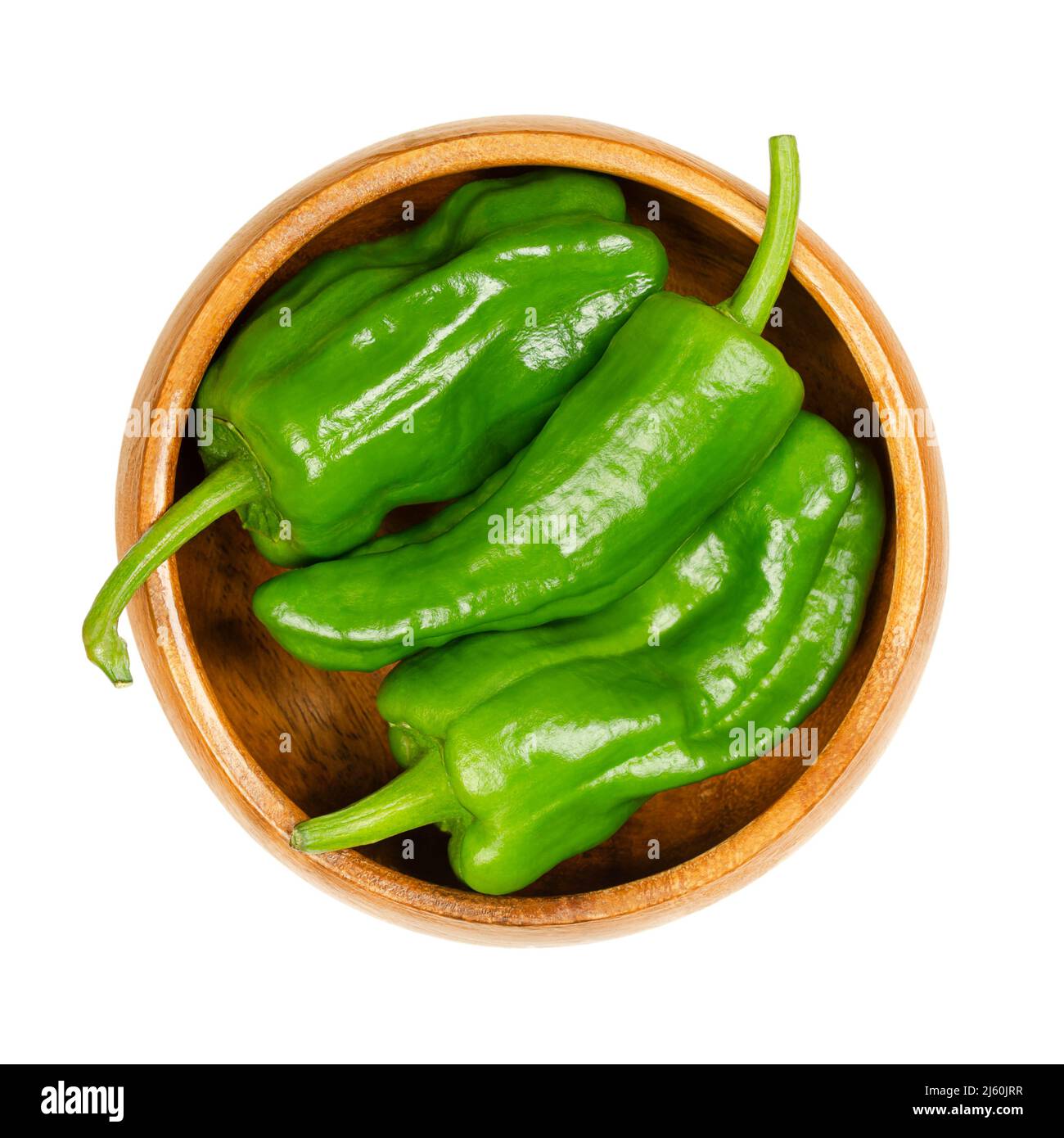 Peperoni Padron crudi, detti anche peperoni di erbe, in una ciotola di legno. Varietà di Capsicum annuum dal comune di Padron nel nord-ovest della Spagna. Foto Stock