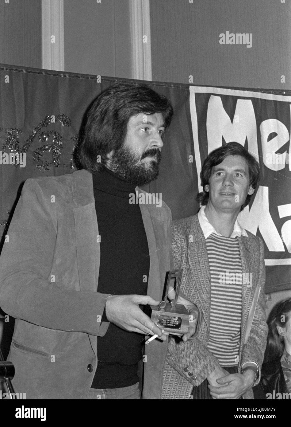 Il batterista John Bonham della rock band inglese LED Zeppelin ha ricevuto un premio in occasione della cerimonia Melody Maker poll Awards tenutasi a Londra nel 1979. Il compere Michael Palin è sullo sfondo. Foto Stock