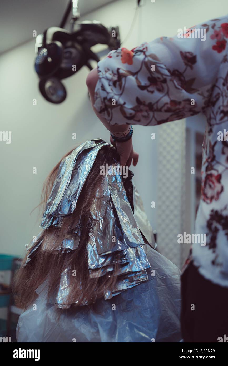 Donna tinge i capelli in un barbiere, il processo di tintura i capelli con la lamina. Foto Stock