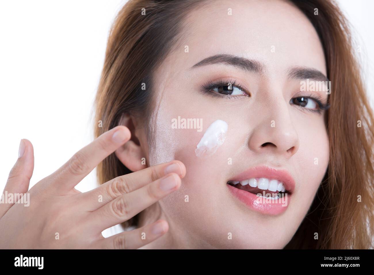 Giovane e bella signora ha strisciato il suo viso con una lozione idratante, su sfondo bianco - foto di scorta Foto Stock