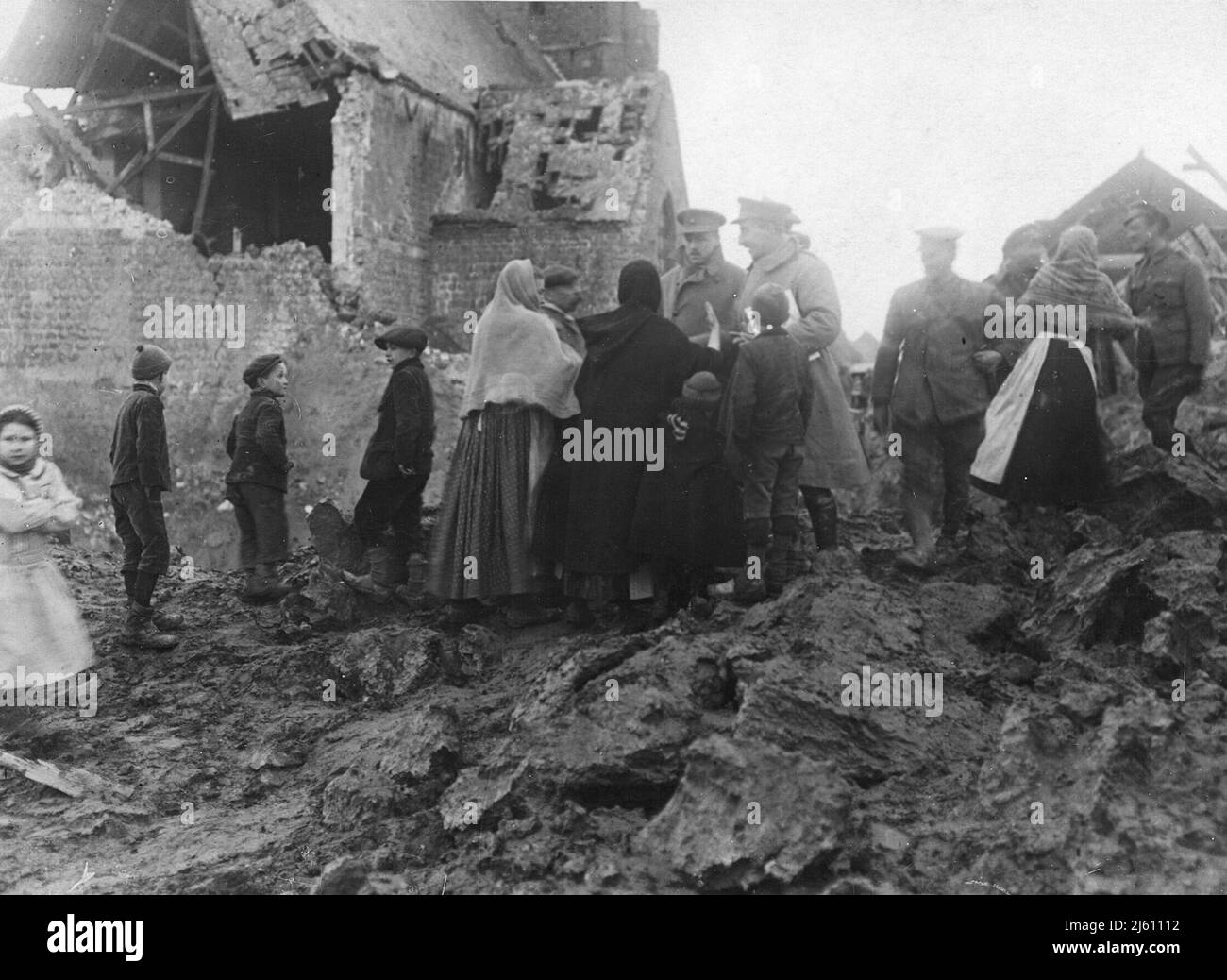 Soldati britannici e civili francesi in piedi in un villaggio in rovina. Foto Stock