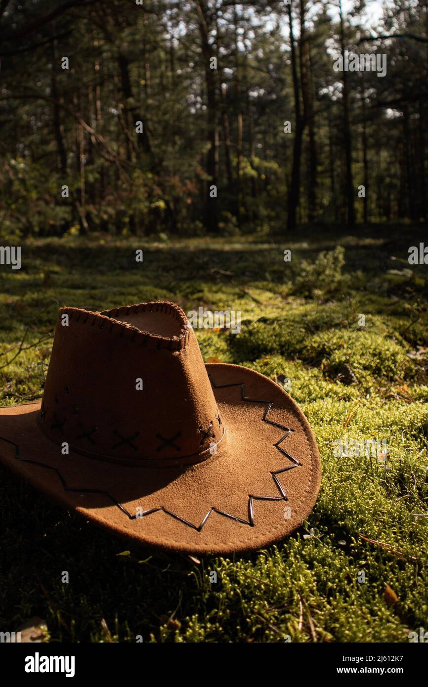 Un cappello occidentale di Cowboy è sdraiato sul muschio in una giornata di sole nella foresta. Foto Stock
