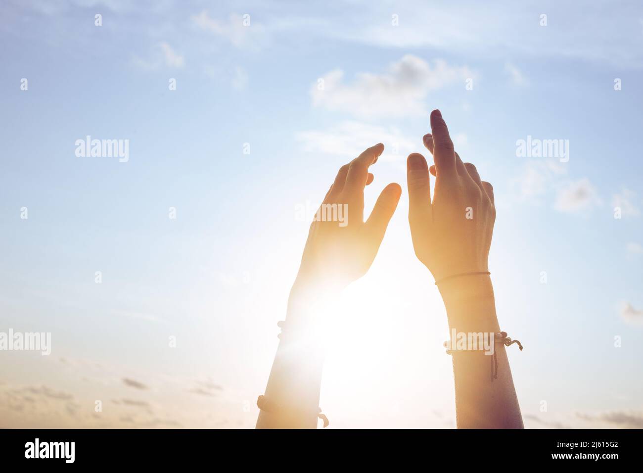 Donna sollevamento mani fino al cielo del tramonto Foto Stock