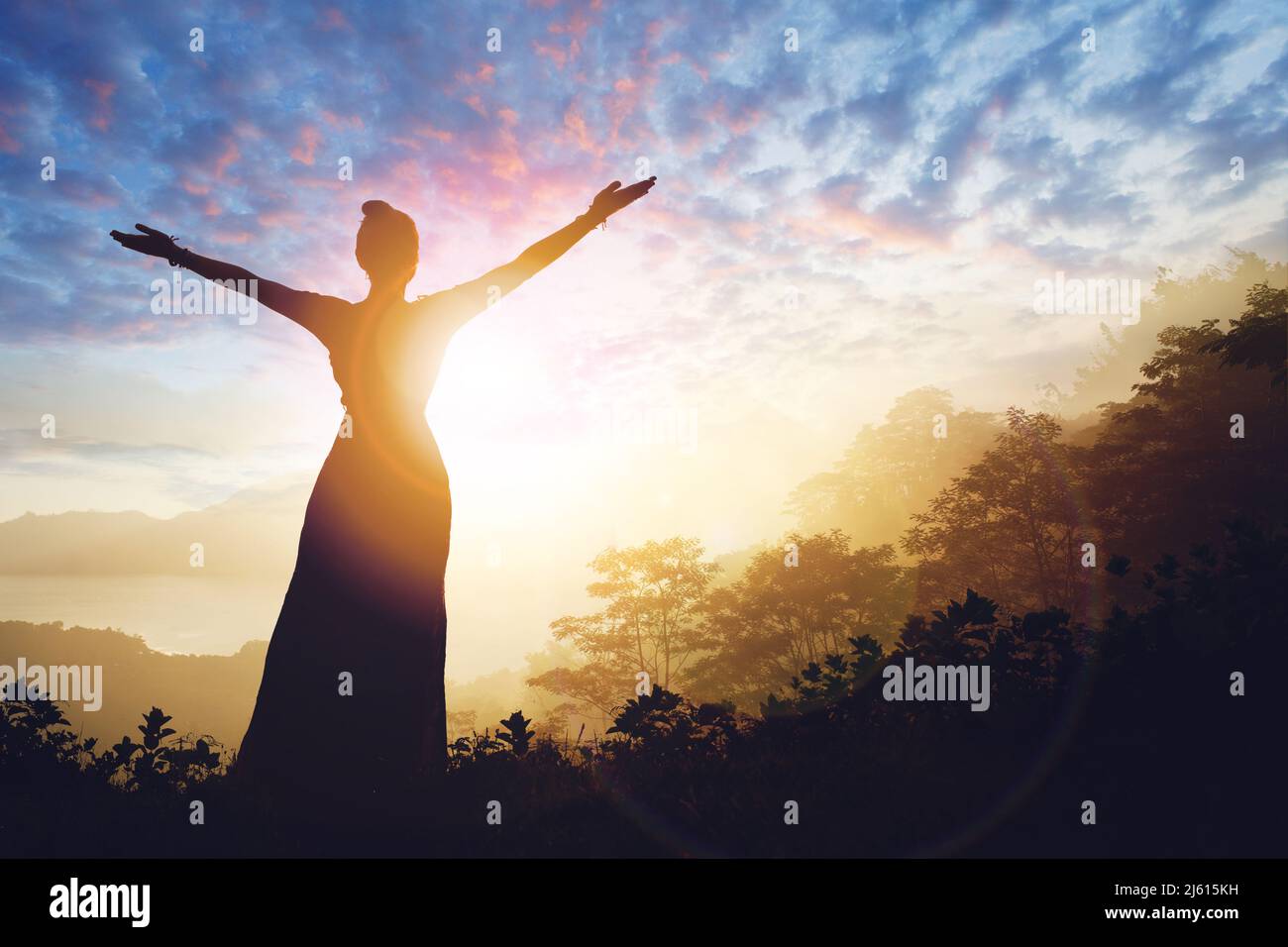 Donna di successo silhouette escursionistica in montagna al tramonto Foto Stock