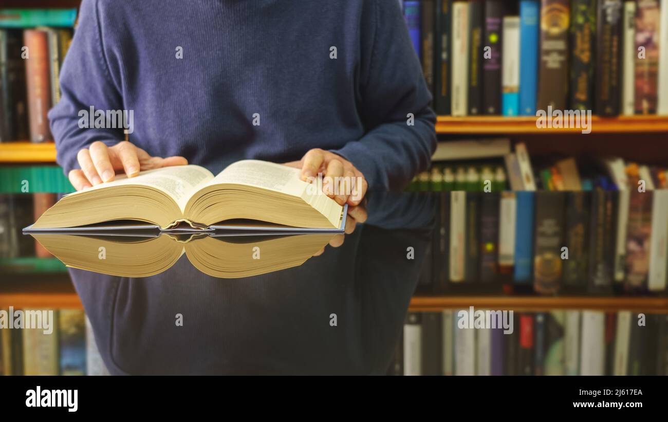 libro di lettura dell'uomo bianco ad un tavolo di vetro e sfondo della libreria con i lotti dei libri. Spazio di copia. Sfondo. Foto Stock