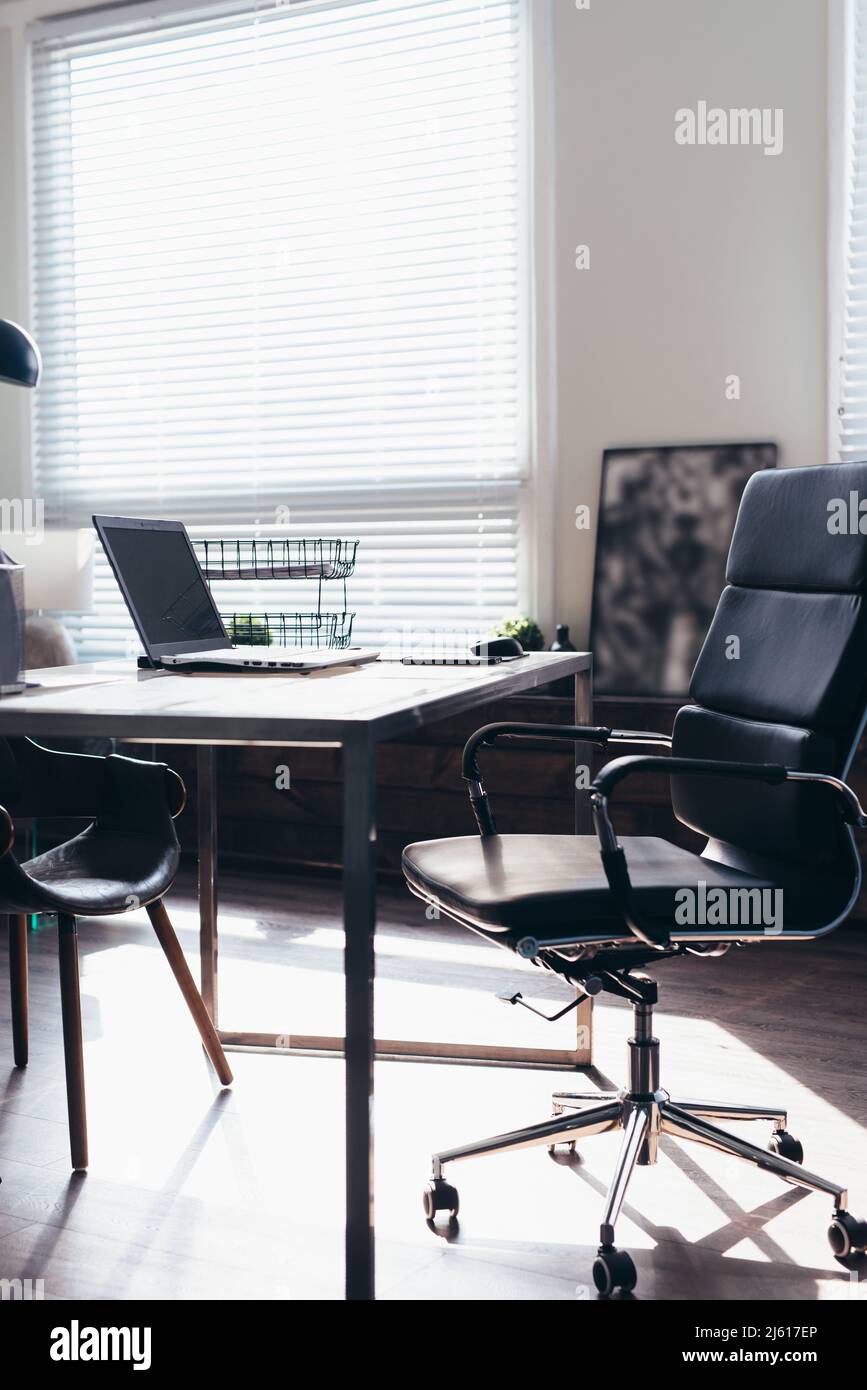 Posto di lavoro in ufficio con sedia e tavolo con computer portatile. Foto Stock