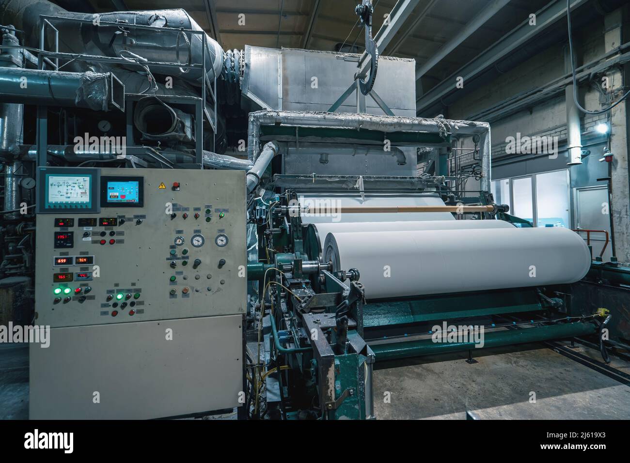 Macchina di produzione con rotoli di carta nuova in fabbrica di riciclaggio della carta di scarto. Foto Stock