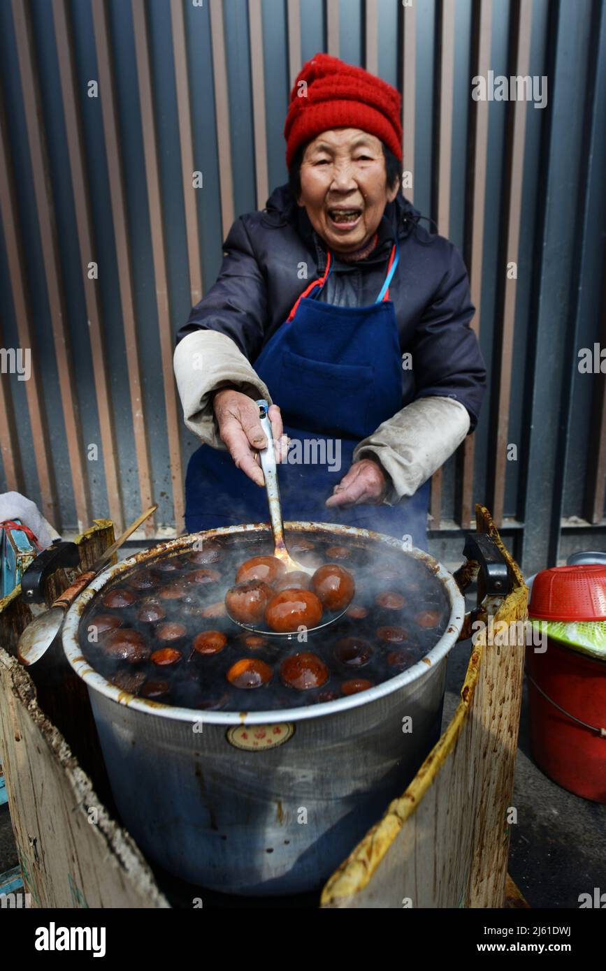 Una donna locale che cucinava uova tradizionali di foglie di tè. Le uova sono cotte in tè, salsa di soia e altre spezie e sono un comune in tutta la Cina. Foto Stock