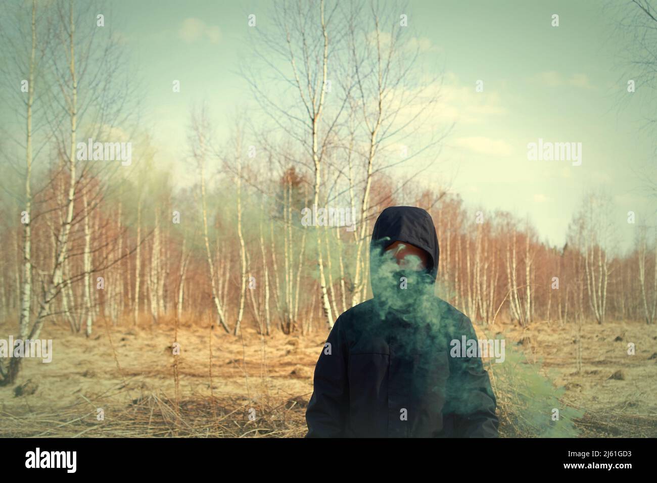 Un preteen in una giacca nera e una maschera tiene una scacchiera con fumo colorato Foto Stock