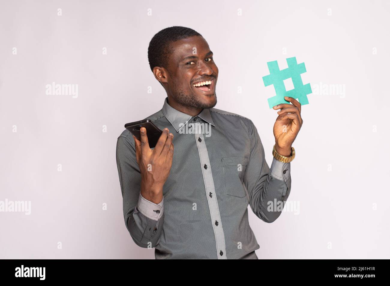 uomo nero eccitato che tiene il telefono e il simbolo dell'etichetta di hash Foto Stock
