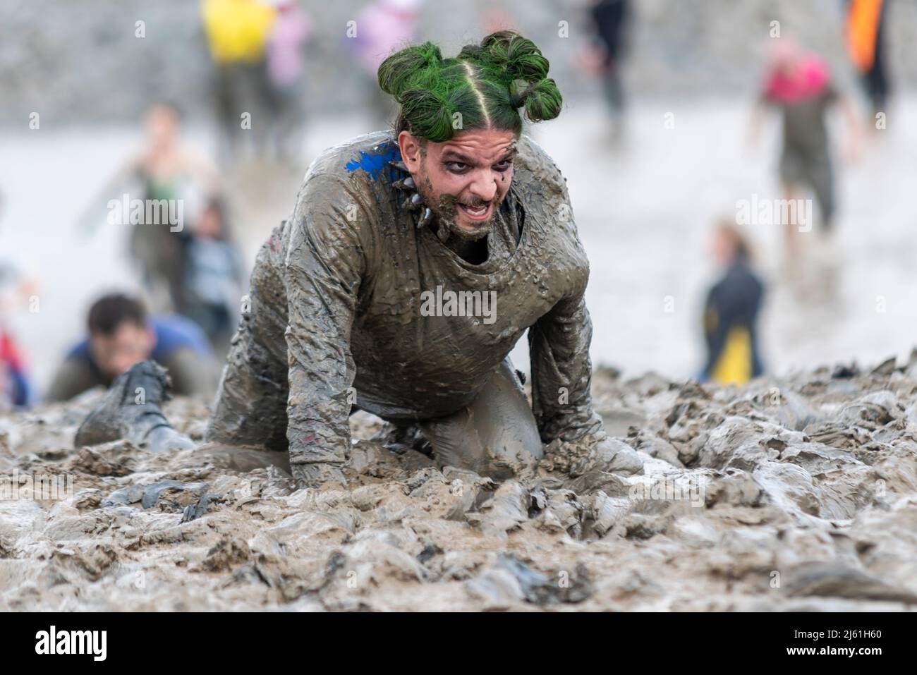 Maschio goth in stile strisciante nel fango alla Maldon Mud Race 2022 sul fiume Blackwater, Essex, Regno Unito. Foto Stock