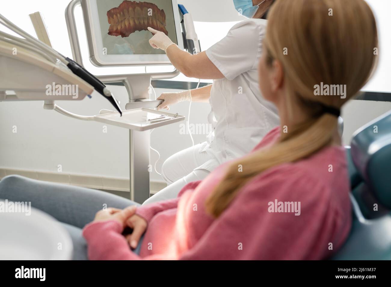 Dentista che spiega l'immagine dei denti sullo schermo del computer al paziente in clinica dentale Foto Stock