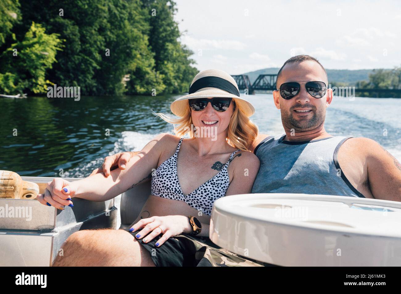 Coppia rilassante con le braccia intorno a vicenda in barca in giorno di sole Foto Stock
