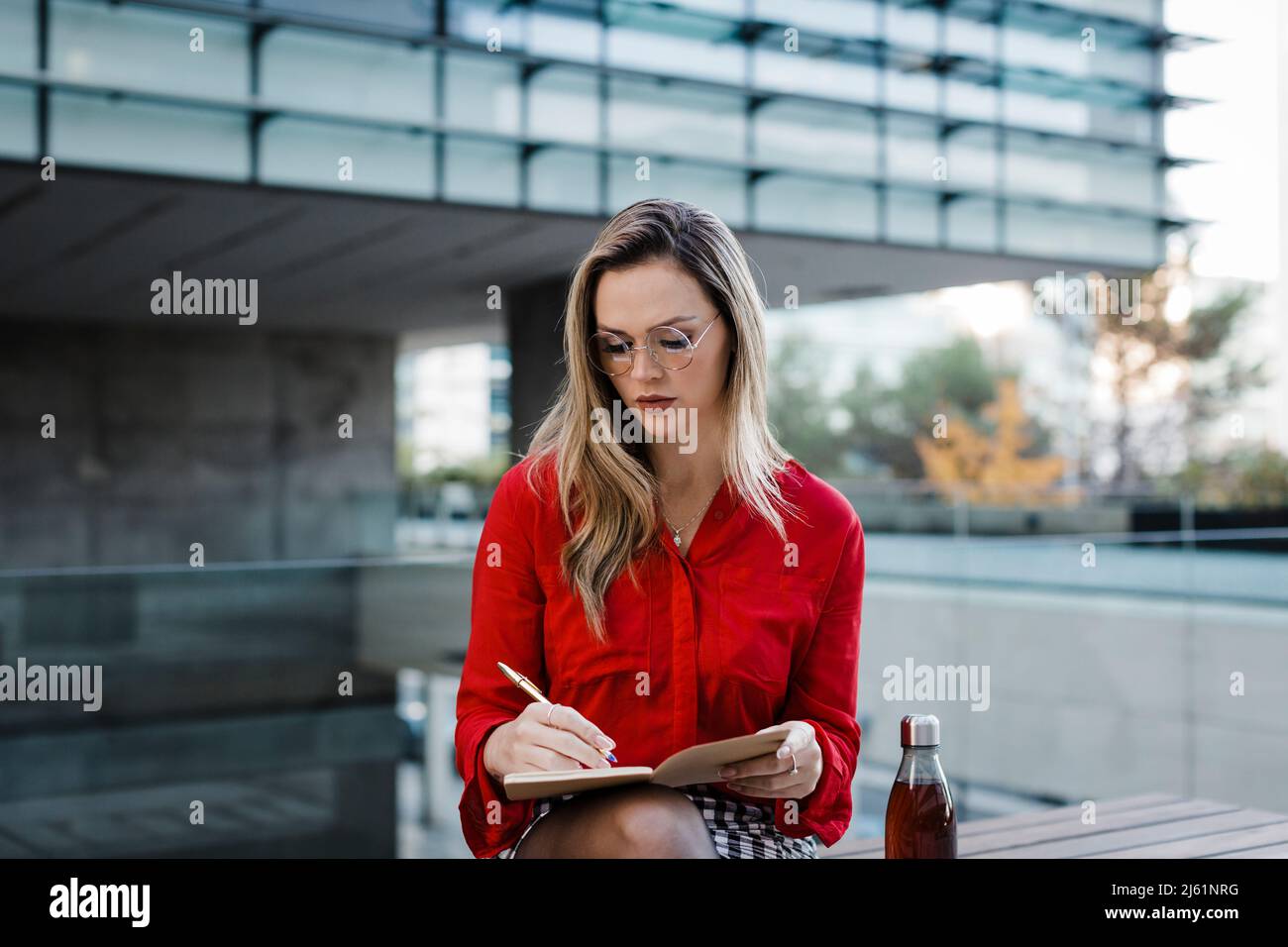 Donna d'affari che scrive nel libro in città Foto Stock