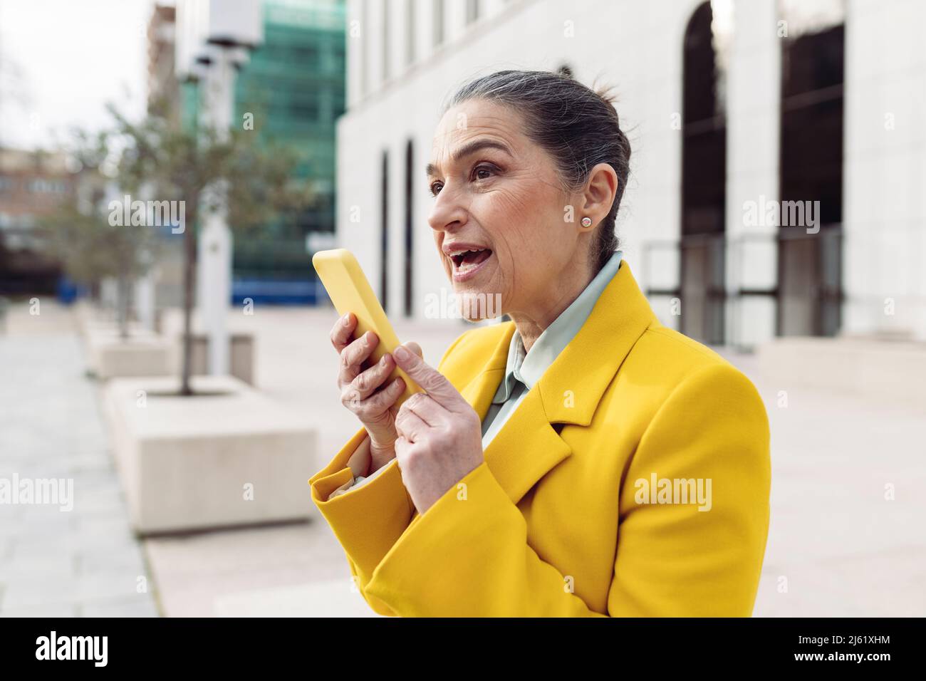 Donna d'affari che invia messaggi vocali tramite telefono cellulare presso il parcheggio dell'ufficio Foto Stock