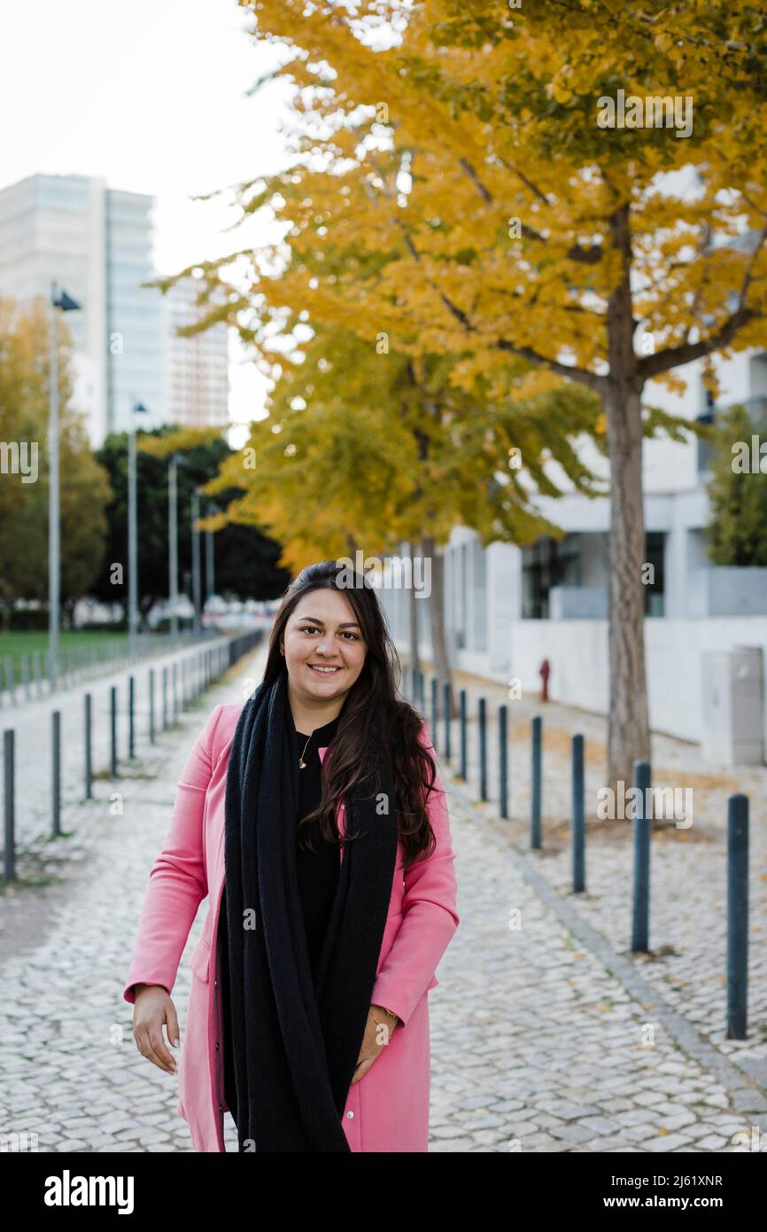Donna sorridente in piedi sul marciapiede nel parco pubblico Foto Stock