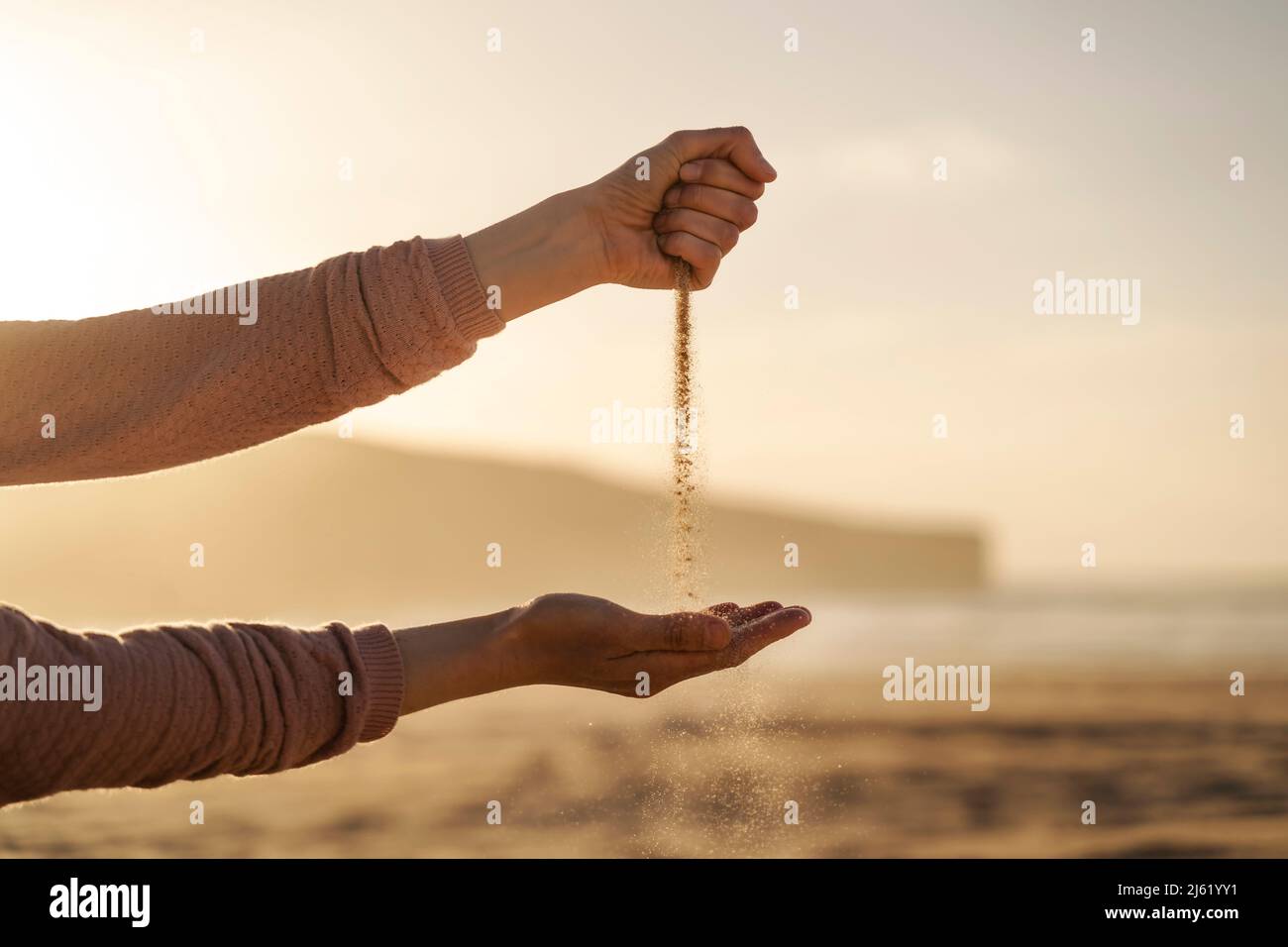 Sabbia che cade dal pugno chiuso al tramonto Foto Stock
